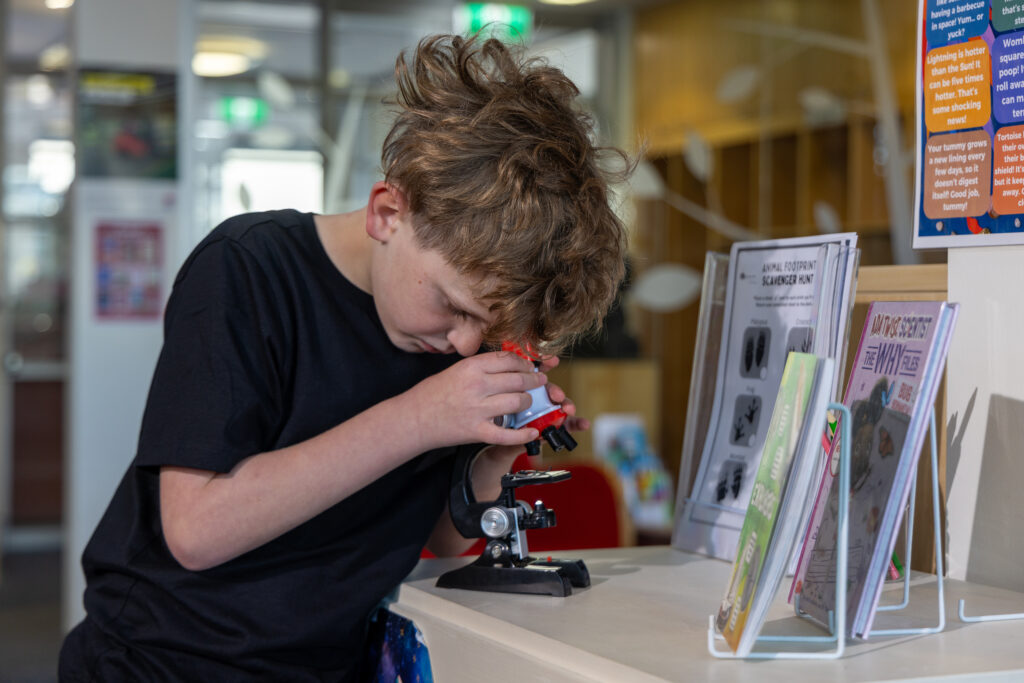 kid looking through a microscope at THE BOWRAL CITY LIBRARY