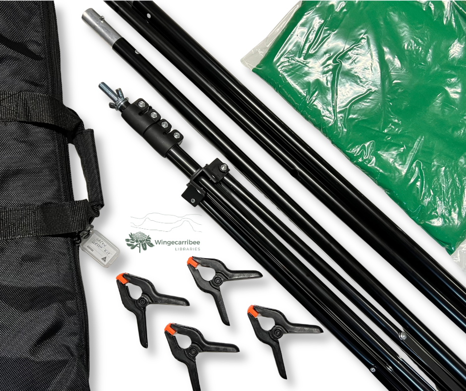 Green screen kit on a table with all the contents laid out: a carry bag, green screen, assembly arms and clips to hold up the screen.